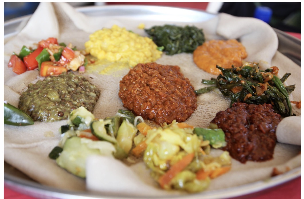 A traditional Ethiopian injera platter with an array of colorful stews and vegetables